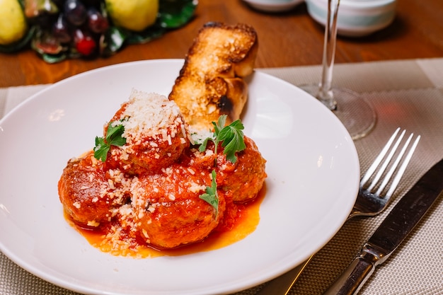 Assiette de boulettes de viande garnie de sauce tomate parmesan râpé et persil servi avec du pain grillé