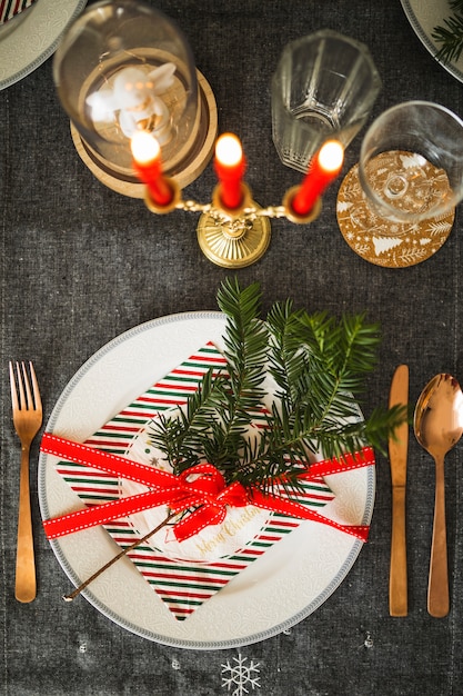 Photo gratuite assiette avec brindille et ruban près de couverts et de bougies