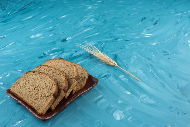 Une assiette brune avec du pain de mie et de l'oreille sur fond bleu.