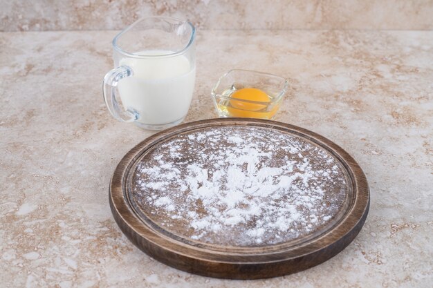 Une assiette brune de farine et une tasse en verre de lait