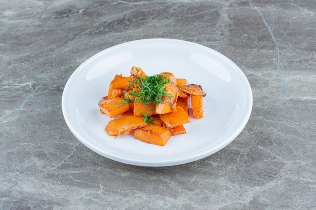 Une assiette de carottes tranchées, sur la table en marbre.