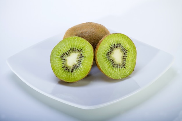 assiette carrée blanche avec quelques deux kiwis