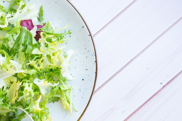 Assiette en céramique blanche avec salade fraîche sur une surface en bois