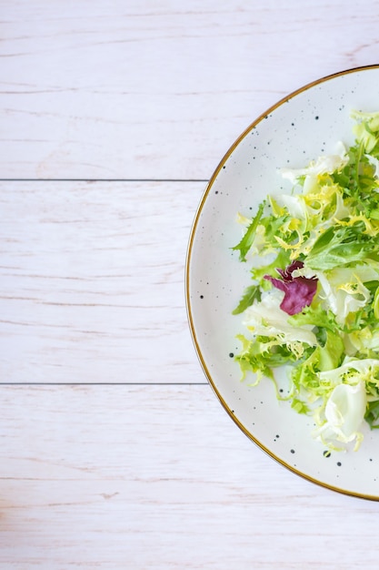 Assiette en céramique blanche avec salade fraîche sur une surface en bois