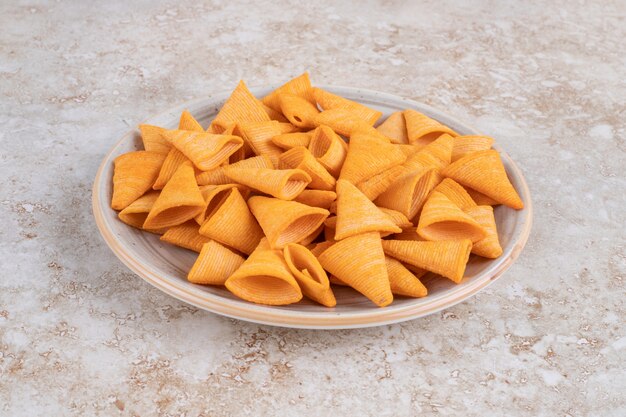 Assiette en céramique de chips triangulaires croquantes sur marbre.