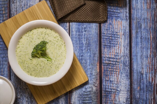 Assiette de crème de brocoli sur une table en bois bleu