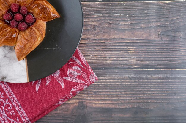 Une assiette de délicieuse pâtisserie aux framboises posée sur une table en bois.