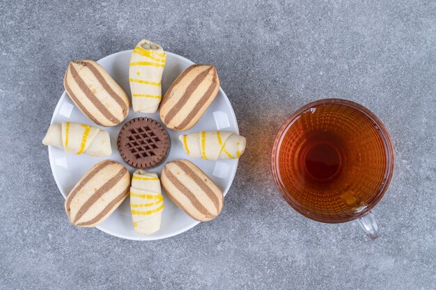 Assiette de divers biscuits et verre de thé sur une surface en marbre