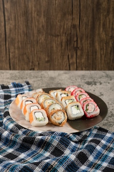 Assiette de divers délicieux rouleaux de sushi sur table en marbre