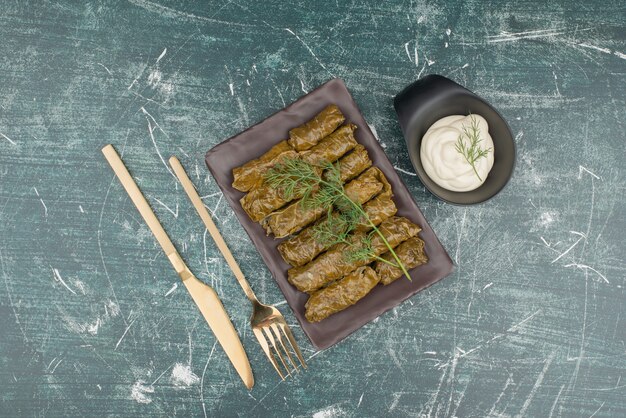 Assiette de dolma et crème sure sur une surface en marbre.