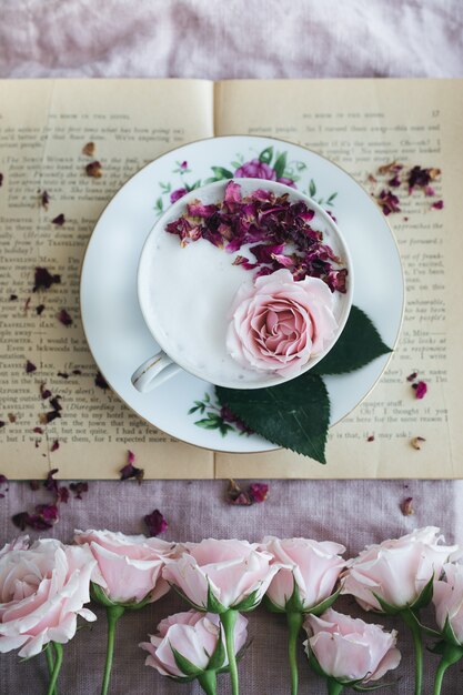 Assiette florale ronde blanche et rose avec une tasse de thé et de roses
