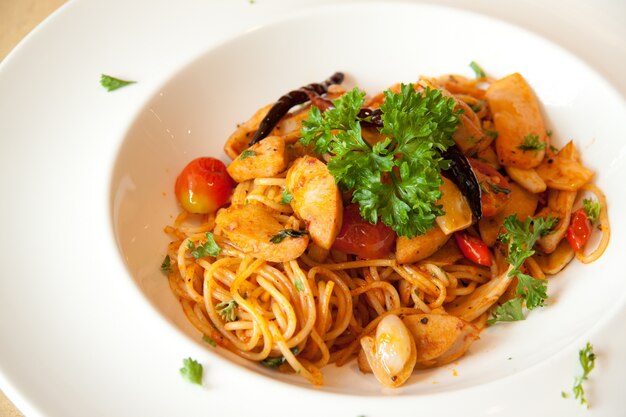 Assiette fraîchement cuite de spaghetti avec saucisse saupoudrée d&#39;herbes fraîches et vertes.