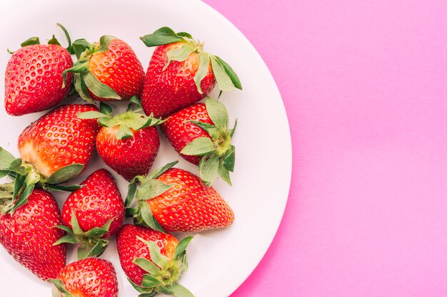 Assiette de fraises sur fond rose