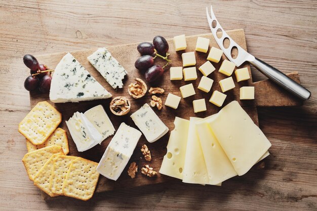 Assiette de fromages avec différents arts du fromage raisin et noix servi sur planche de bois