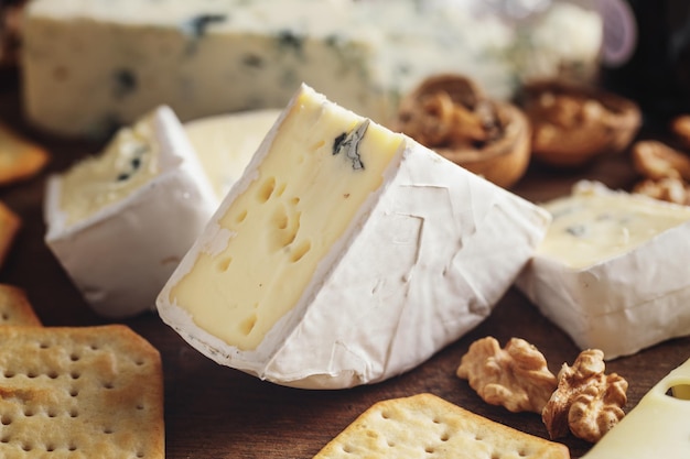 Assiette de fromages avec différents arts de fromage raisin et noix servis sur planche de bois.