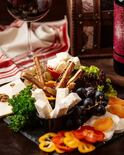Assiette de fromages vue de face avec des raisins et un verre de vin rouge