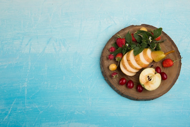 Photo gratuite assiette de fruits ronde avec poires, pommes et baies sur le côté droit