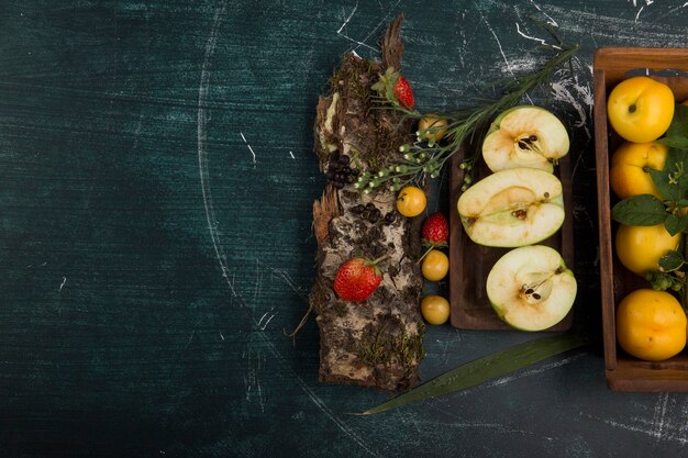 Assiette de fruits ronde avec poires, pommes et baies sur fond mat, dans le côté droit