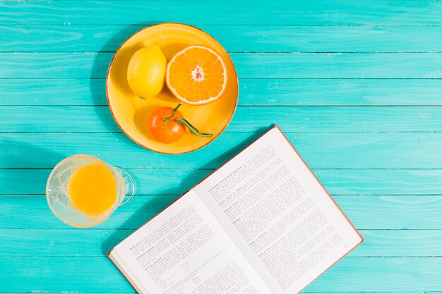 Assiette de fruits, verre à jus et livre sur la table