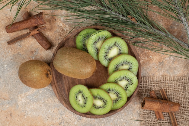 Photo gratuite assiette de kiwi frais et bâtons de cannelle sur une surface en marbre.