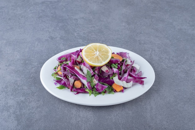 Une assiette de légumes râpés au citron , sur la surface en marbre.