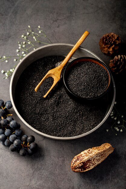 Assiette métallique grise remplie de graines de pavot et de raisins sur fond gris