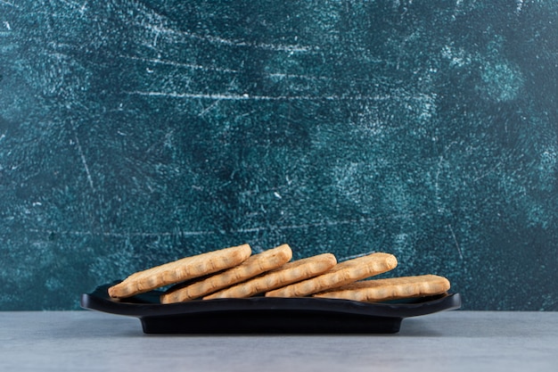 Photo gratuite assiette noire de délicieux biscuits placés sur fond de pierre.
