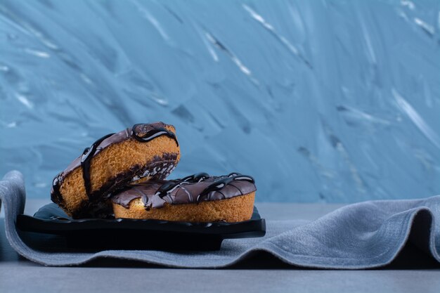 Une assiette noire de deux gâteaux au chocolat sucré frais sur une nappe.