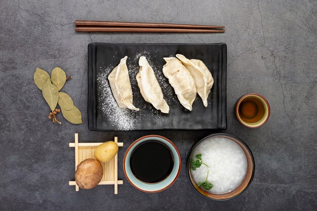 Assiette noire de dim sum avec bol de soupe de riz sur fond gris