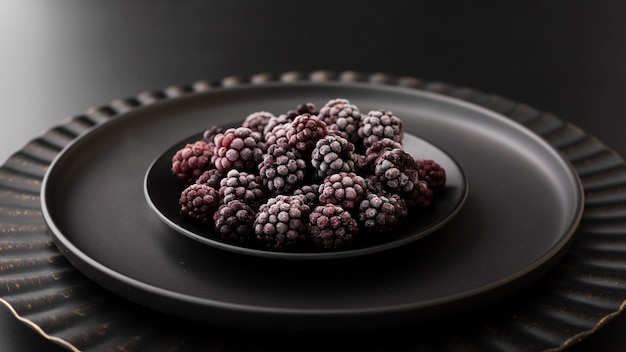 Photo gratuite assiette noire avec des mûres sur une table sombre