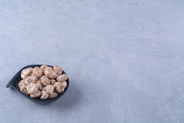 Une assiette noire pleine de céréales saines sur une table grise.