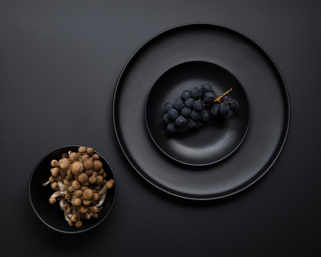 Assiette noire avec des raisins sur fond noir