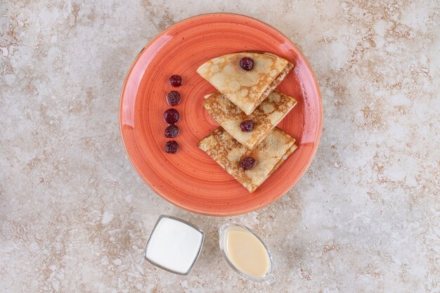 Une assiette d'orange avec de savoureuses crêpes minces et des baies