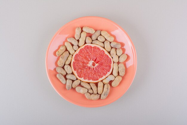 Assiette orange de tranche de pamplemousse et cacahuètes biologiques sur fond blanc. photo de haute qualité