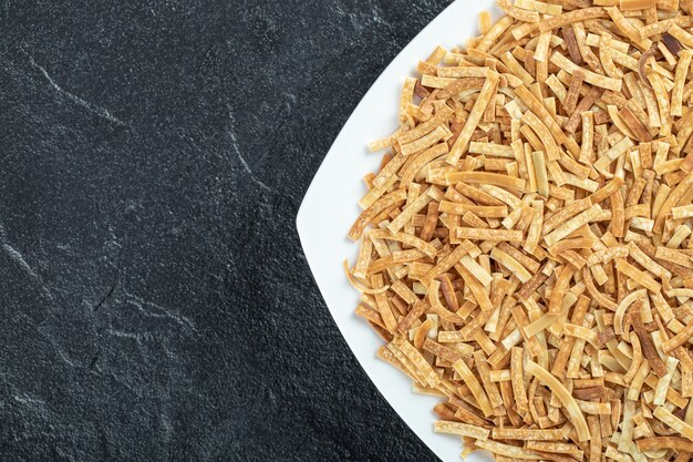 Assiette de pâtes crues sur fond noir.