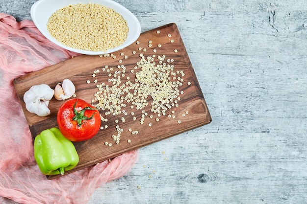 Une assiette de pâtes et légumes crus en forme d'étoile sur la planche de bois.