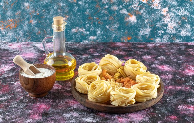 Assiette de pâtes variées avec bol de farine et d'huile.