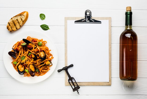 Assiette plate de pâtes de moules et de vin avec le presse-papiers