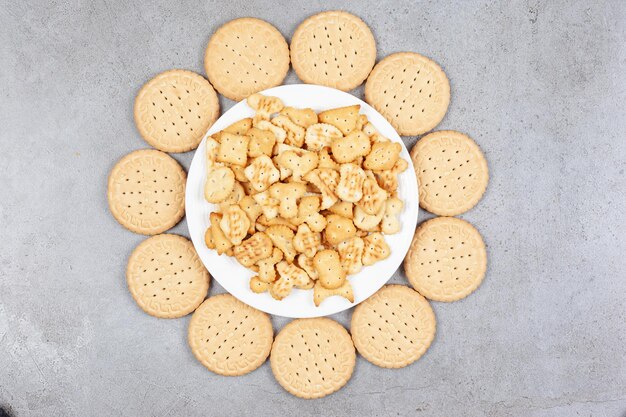Assiette pleine de chips de biscuits entourée de biscuits sur fond de marbre. Photo de haute qualité