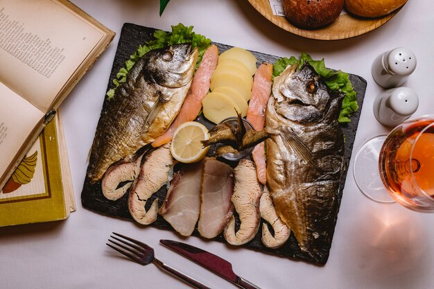 Assiette de poisson vue de dessus avec pommes de terre et une tranche de citron avec un verre de vin