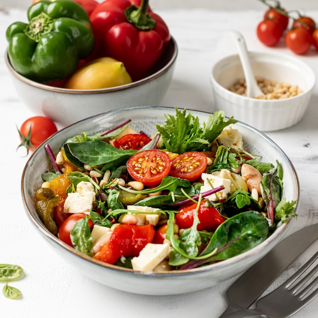 Une assiette avec des poivrons cuits au four, des haricots et des tomates sur un fond blanc