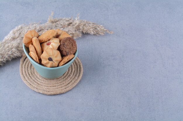 Une assiette profonde bleue avec différents biscuits sucrés sur un sac.