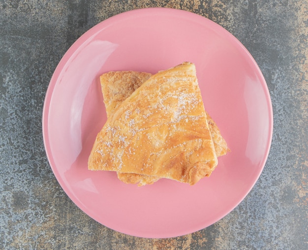 Photo gratuite une assiette rose de deux tartes triangulaires maison avec du sucre