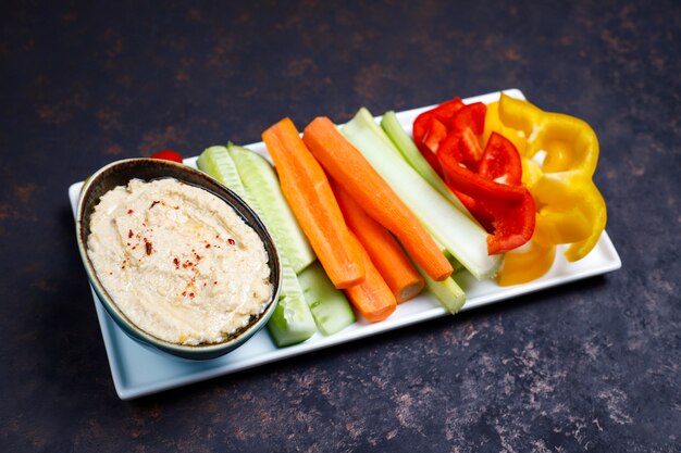 Assiette de salade de légumes biologiques frais avec houmous sur une surface marron foncé ou béton