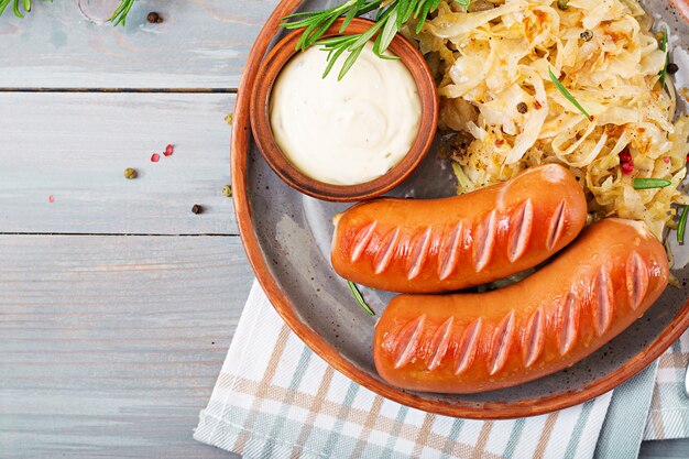 Assiette de saucisses et choucroute sur table en bois. Menu traditionnel de l'Oktoberfest. Mise à plat. Vue de dessus.