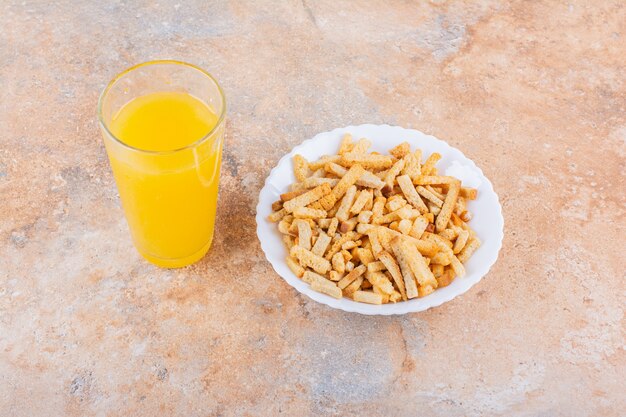 Assiette de savoureux craquelins croustillants et verre de jus sur fond de marbre. photo de haute qualité