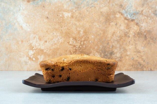 Une assiette sombre avec un délicieux gâteau frais sur blanc