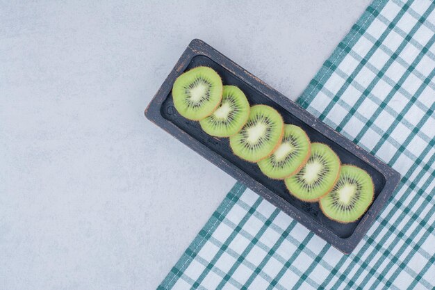 Une assiette sombre de kiwi frais tranché sur nappe. photo de haute qualité