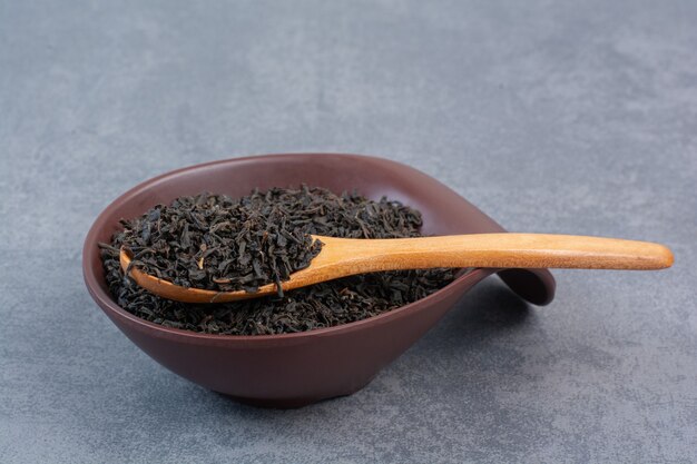 Une assiette sombre pleine d'infusion avec une cuillère en bois.