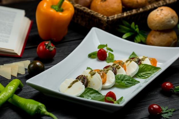 Une assiette suqare de mozarella hachée, de cerises et de feuilles de menthe.